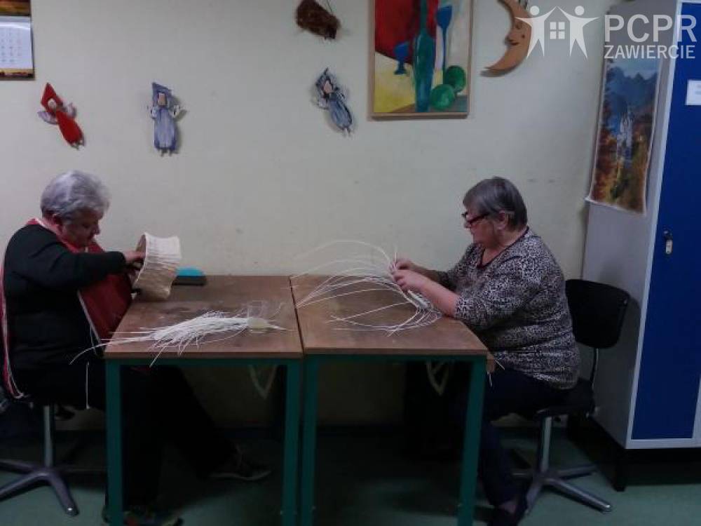 Zdjęcie: Dwie kobiety siedzą przy stole i trzymają rattanowe gałązki
